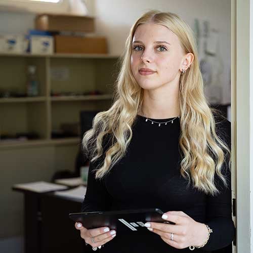 blonde Haare, schwarzes Oberteil, lange Ärmel, Halskette, Kartenhalter